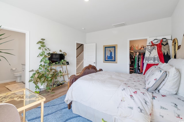 bedroom with hardwood / wood-style flooring, a spacious closet, a closet, and ensuite bathroom