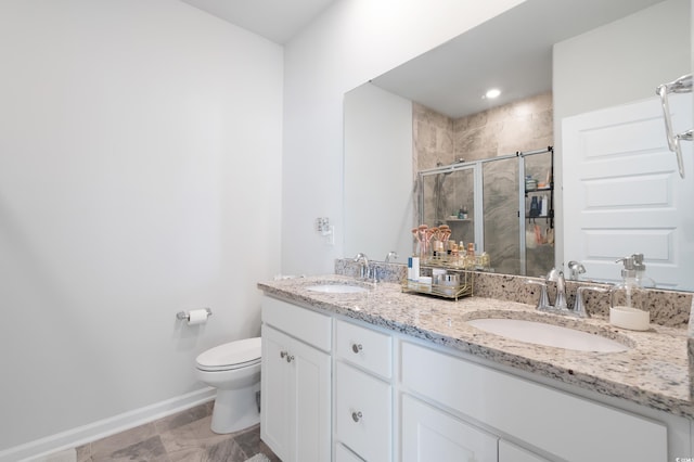 bathroom featuring a shower with door, vanity, and toilet