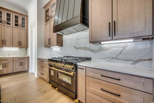 kitchen with tasteful backsplash, double oven range, light stone counters, and premium range hood