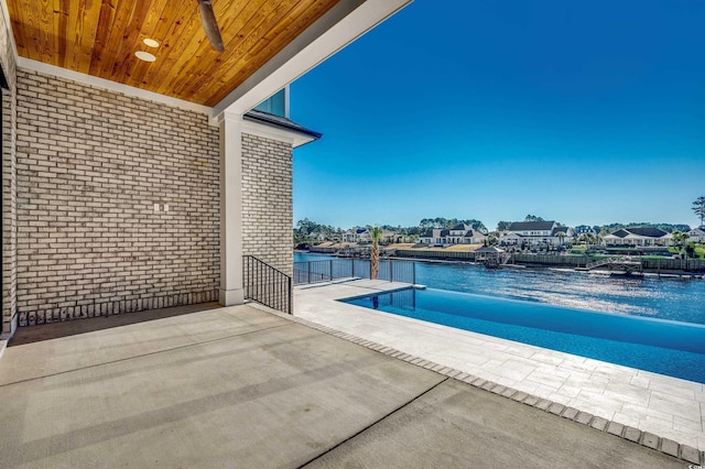 view of swimming pool featuring a water view, ceiling fan, and a patio