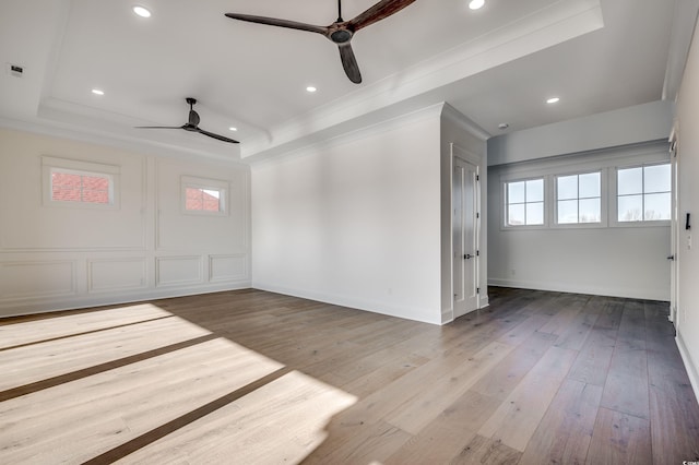 spare room featuring ceiling fan, light wood-type flooring, and a tray ceiling