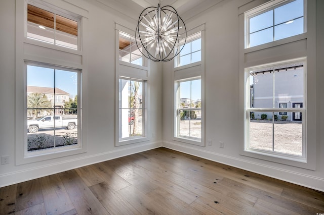 unfurnished dining area with hardwood / wood-style floors, plenty of natural light, and a notable chandelier