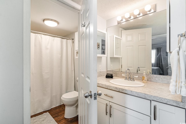 bathroom featuring wood-type flooring, vanity, a textured ceiling, and toilet