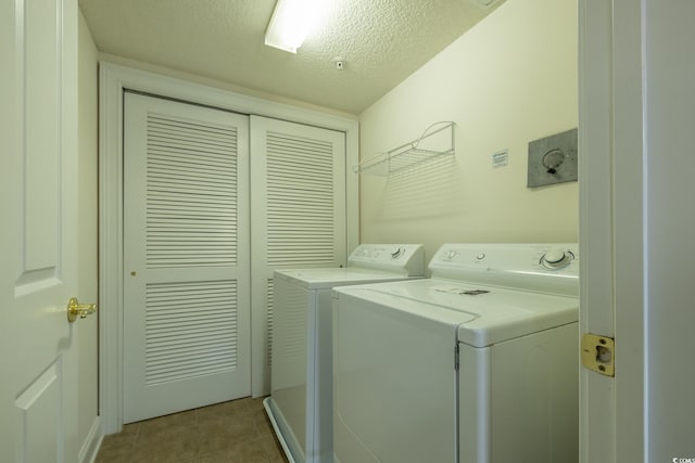 washroom featuring light tile patterned flooring, washer and clothes dryer, and a textured ceiling