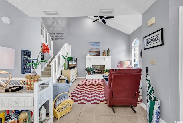 living room featuring a textured ceiling, a fireplace, light tile patterned floors, and lofted ceiling