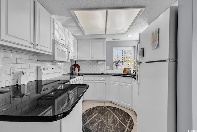 kitchen with white cabinetry, a textured ceiling, white appliances, decorative backsplash, and light tile patterned floors