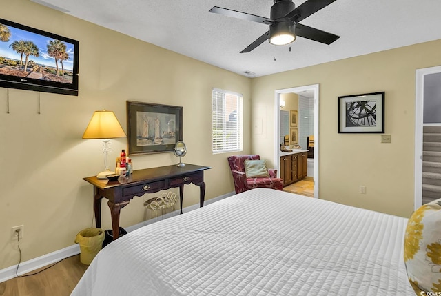 bedroom with ensuite bathroom, ceiling fan, light hardwood / wood-style floors, and a textured ceiling