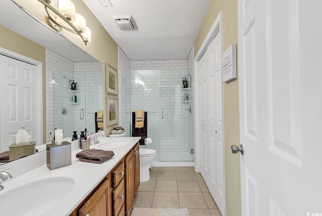 bathroom with tile patterned floors, an enclosed shower, a textured ceiling, toilet, and vanity