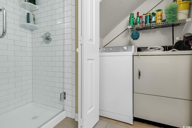 bathroom with tile patterned flooring, a textured ceiling, separate washer and dryer, and a shower with door