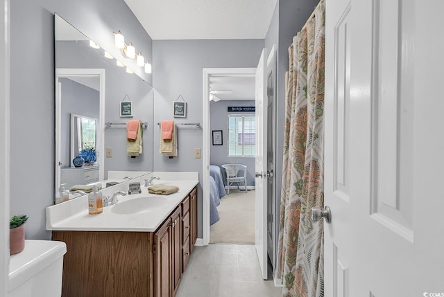 bathroom featuring tile patterned flooring, vanity, a textured ceiling, and a healthy amount of sunlight