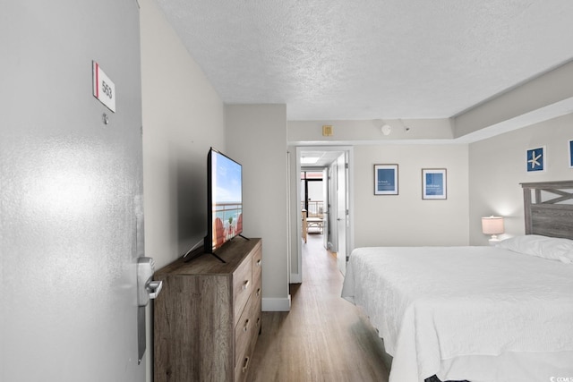 bedroom with light wood-type flooring and a textured ceiling