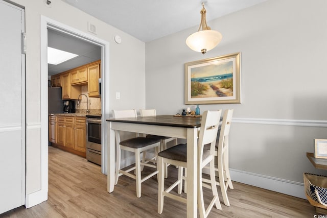 dining space featuring sink and light wood-type flooring