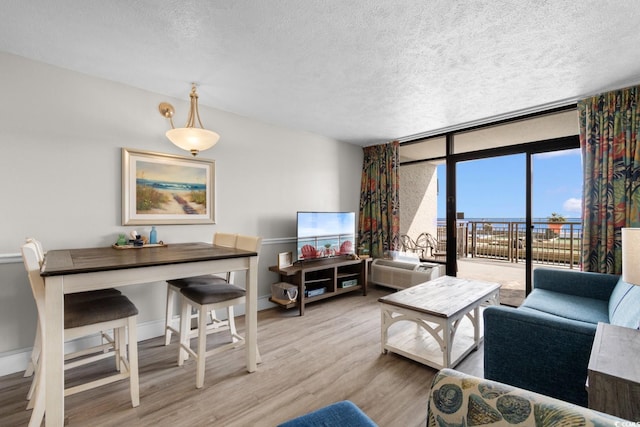 living room with hardwood / wood-style floors, expansive windows, a textured ceiling, and a wall mounted AC