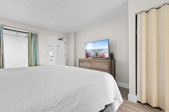 bedroom with light hardwood / wood-style floors and a textured ceiling