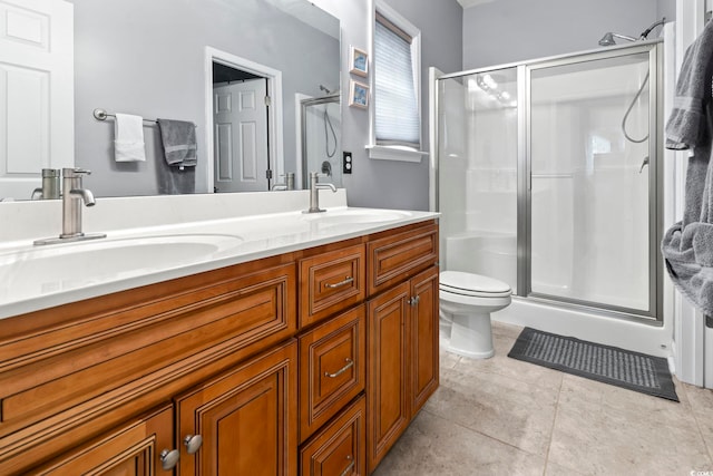 bathroom featuring toilet, vanity, tile patterned floors, and a shower with door