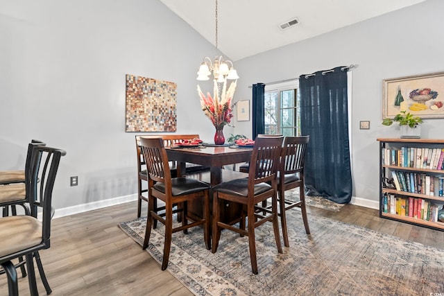 dining area featuring hardwood / wood-style floors, lofted ceiling, and a chandelier