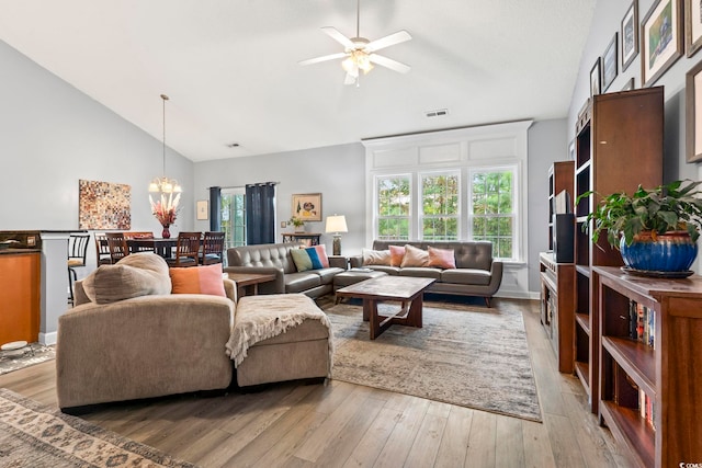 living room featuring ceiling fan with notable chandelier, light wood-type flooring, and high vaulted ceiling