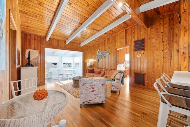 living room featuring wood-type flooring, vaulted ceiling with beams, and wooden walls