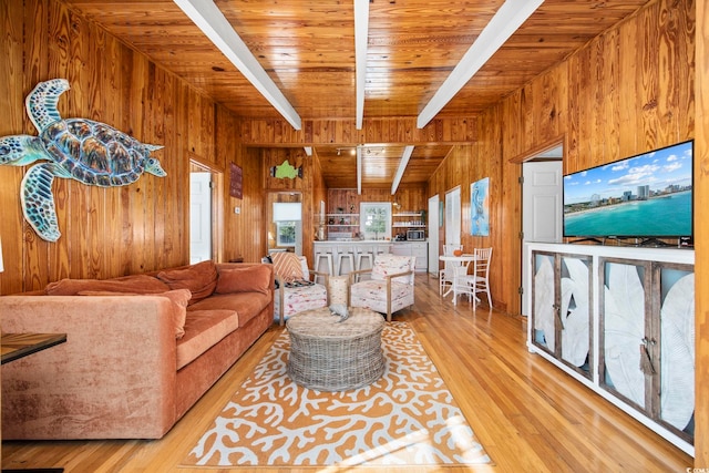 living room featuring beamed ceiling, light wood-type flooring, wood walls, and wood ceiling