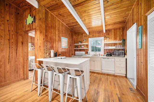 kitchen featuring beam ceiling, wooden walls, a center island, and white appliances