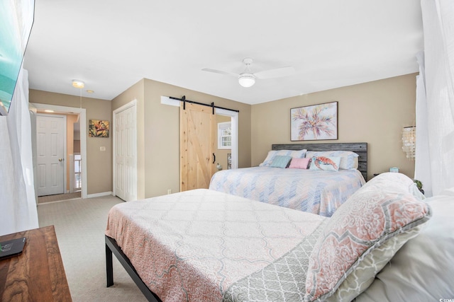 carpeted bedroom featuring ceiling fan and a barn door