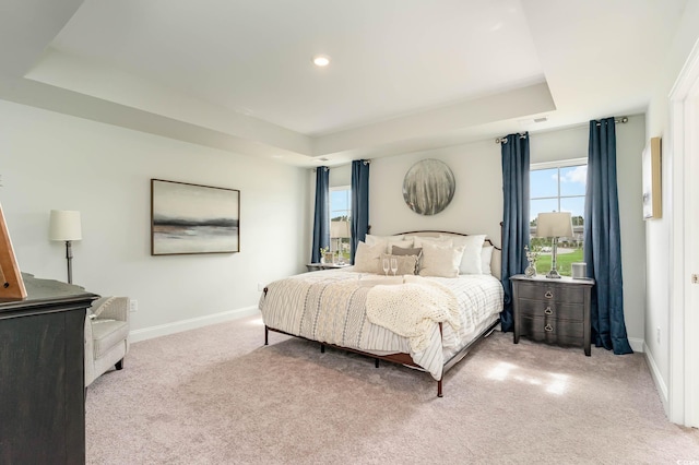 bedroom featuring a raised ceiling and light colored carpet