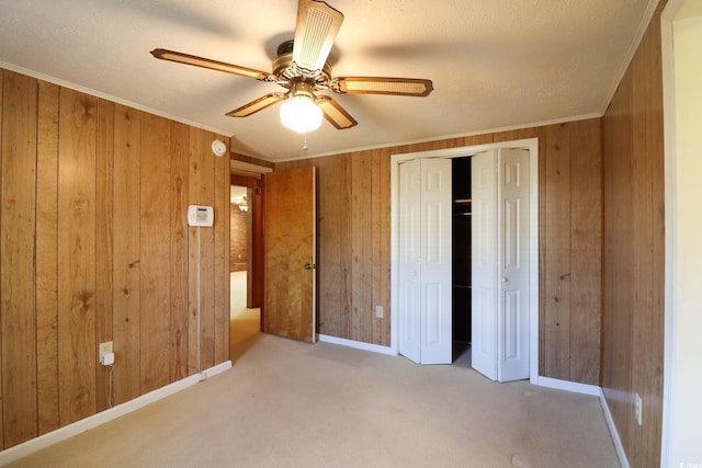 unfurnished bedroom with ceiling fan, crown molding, carpet floors, and wood walls