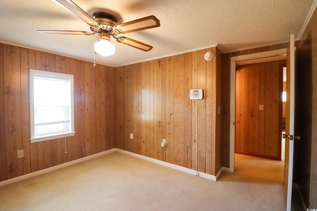 unfurnished room with ceiling fan, ornamental molding, light carpet, and wooden walls