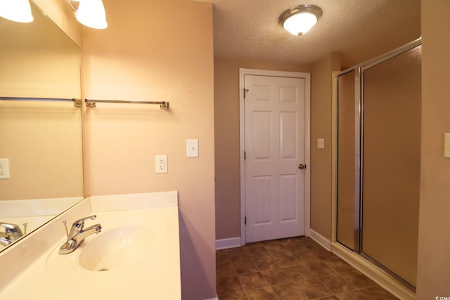 bathroom with sink, a textured ceiling, and walk in shower