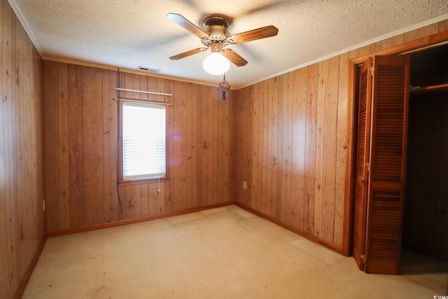 empty room featuring light carpet, ceiling fan, and wood walls