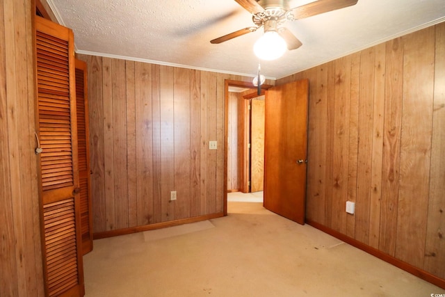 unfurnished bedroom featuring ceiling fan, wooden walls, light carpet, and ornamental molding