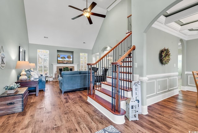 stairway with ceiling fan, high vaulted ceiling, ornamental molding, and hardwood / wood-style flooring