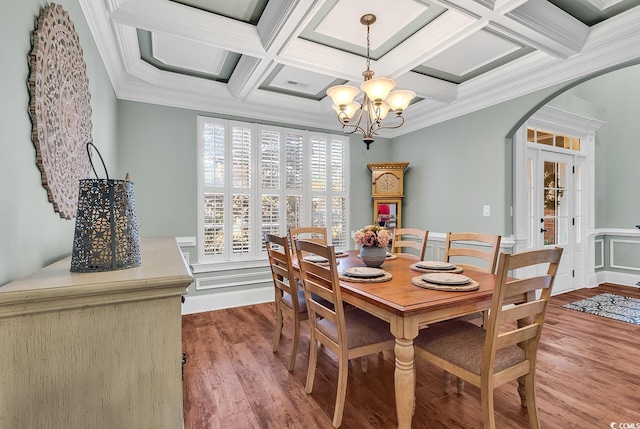 dining room with beam ceiling, coffered ceiling, an inviting chandelier, crown molding, and wood-type flooring