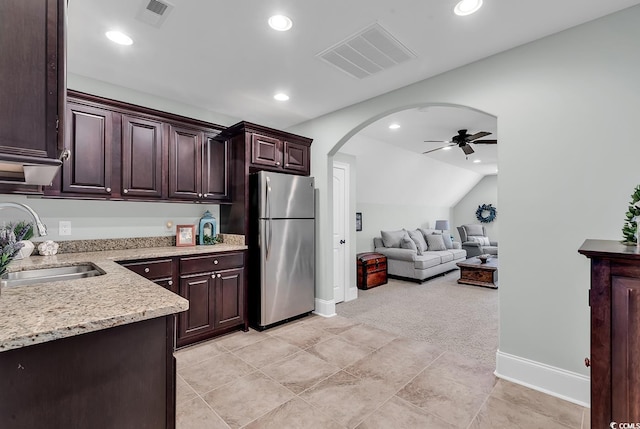 kitchen featuring ceiling fan, sink, stainless steel fridge, lofted ceiling, and dark brown cabinets