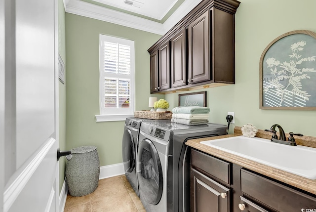 clothes washing area featuring cabinets, ornamental molding, sink, washer and dryer, and light tile patterned floors