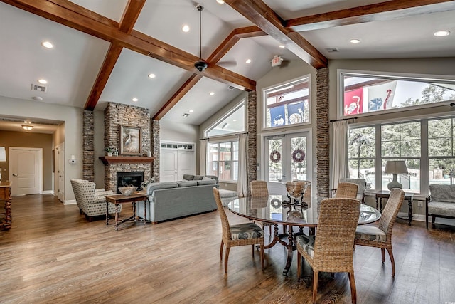 dining area featuring high vaulted ceiling, french doors, light hardwood / wood-style flooring, a fireplace, and beamed ceiling