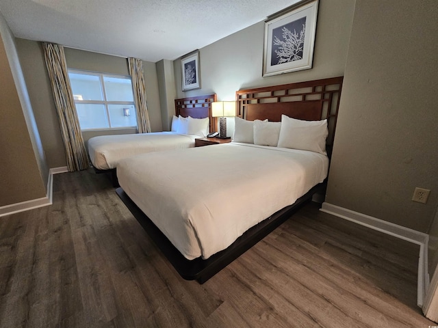 bedroom featuring a textured ceiling and dark hardwood / wood-style flooring