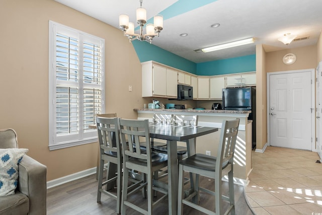 kitchen featuring pendant lighting, a kitchen breakfast bar, light tile patterned floors, a notable chandelier, and white cabinetry