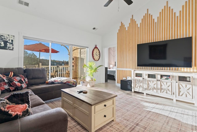 living room featuring ceiling fan, light hardwood / wood-style floors, and vaulted ceiling