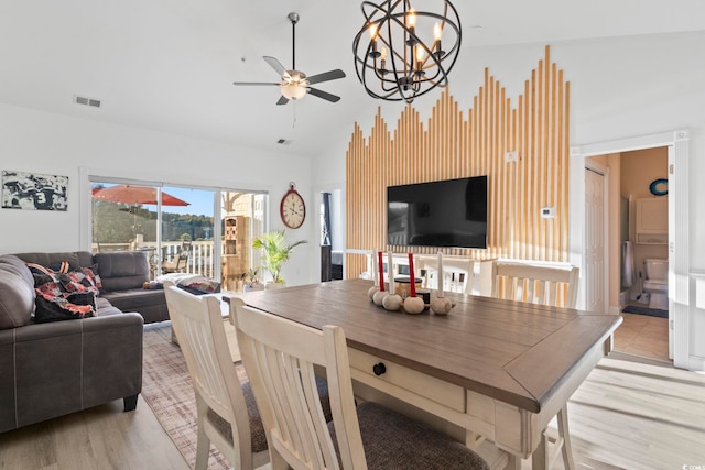 dining space featuring ceiling fan with notable chandelier, light wood-type flooring, and lofted ceiling