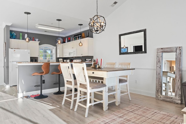 dining space featuring crown molding, light hardwood / wood-style flooring, high vaulted ceiling, and a notable chandelier