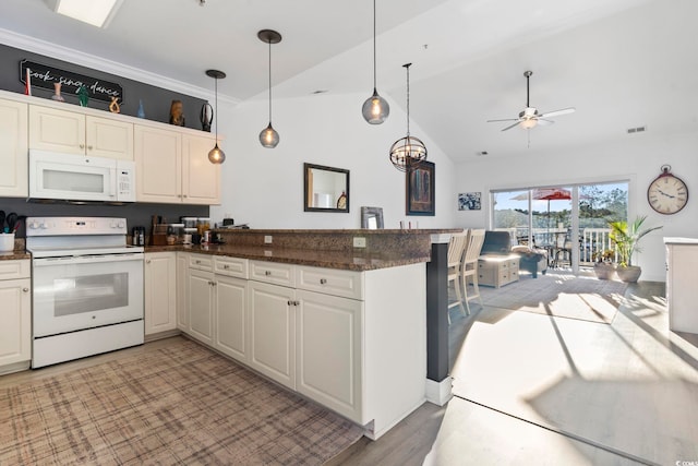 kitchen featuring vaulted ceiling, kitchen peninsula, decorative light fixtures, and white appliances