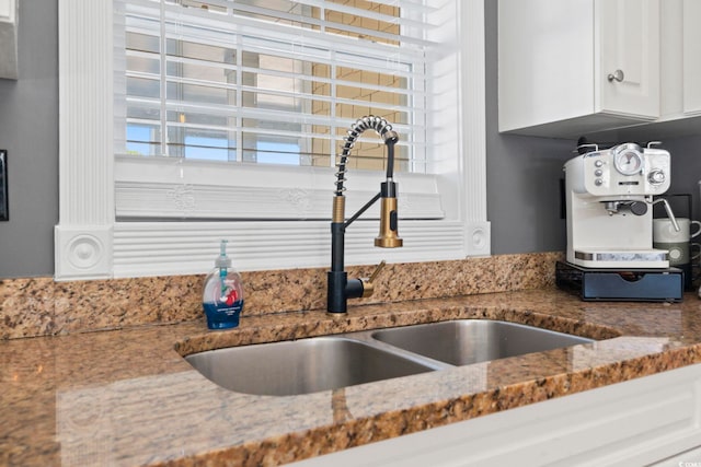 room details with light stone counters, white cabinetry, and sink