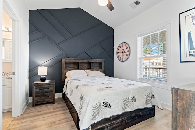 bedroom featuring light wood-type flooring, vaulted ceiling, ceiling fan, and connected bathroom