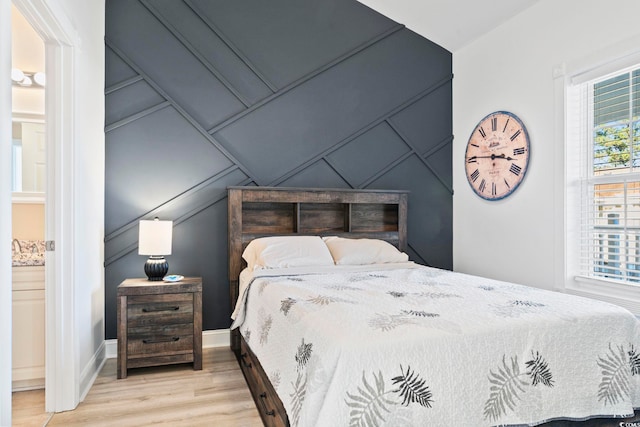 bedroom with light hardwood / wood-style floors and ensuite bath