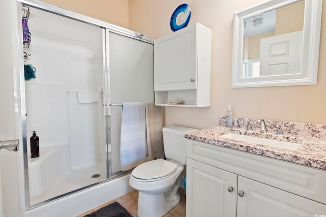 bathroom with tile patterned floors, vanity, a shower with shower door, and toilet