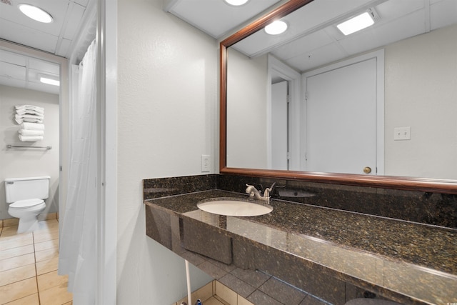 bathroom featuring tile patterned floors, a paneled ceiling, toilet, and sink