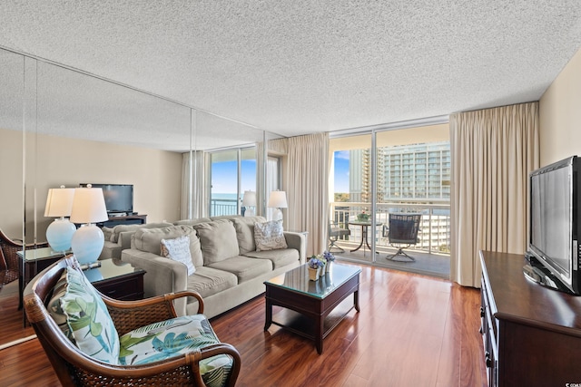 living room featuring hardwood / wood-style floors, a textured ceiling, and a wall of windows