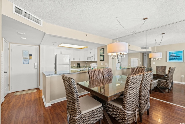 dining area featuring dark hardwood / wood-style floors, sink, and a textured ceiling