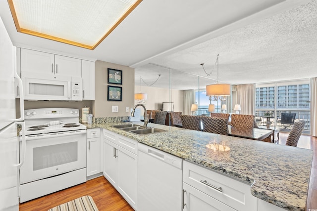 kitchen with kitchen peninsula, light wood-type flooring, white appliances, sink, and white cabinets